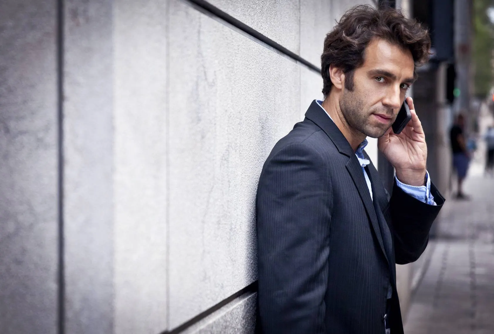 An investigator in a suit taking a phone call on a city street